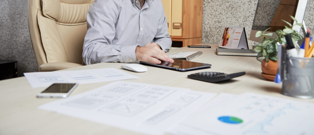 Young bearded businessman using application on tablet computer